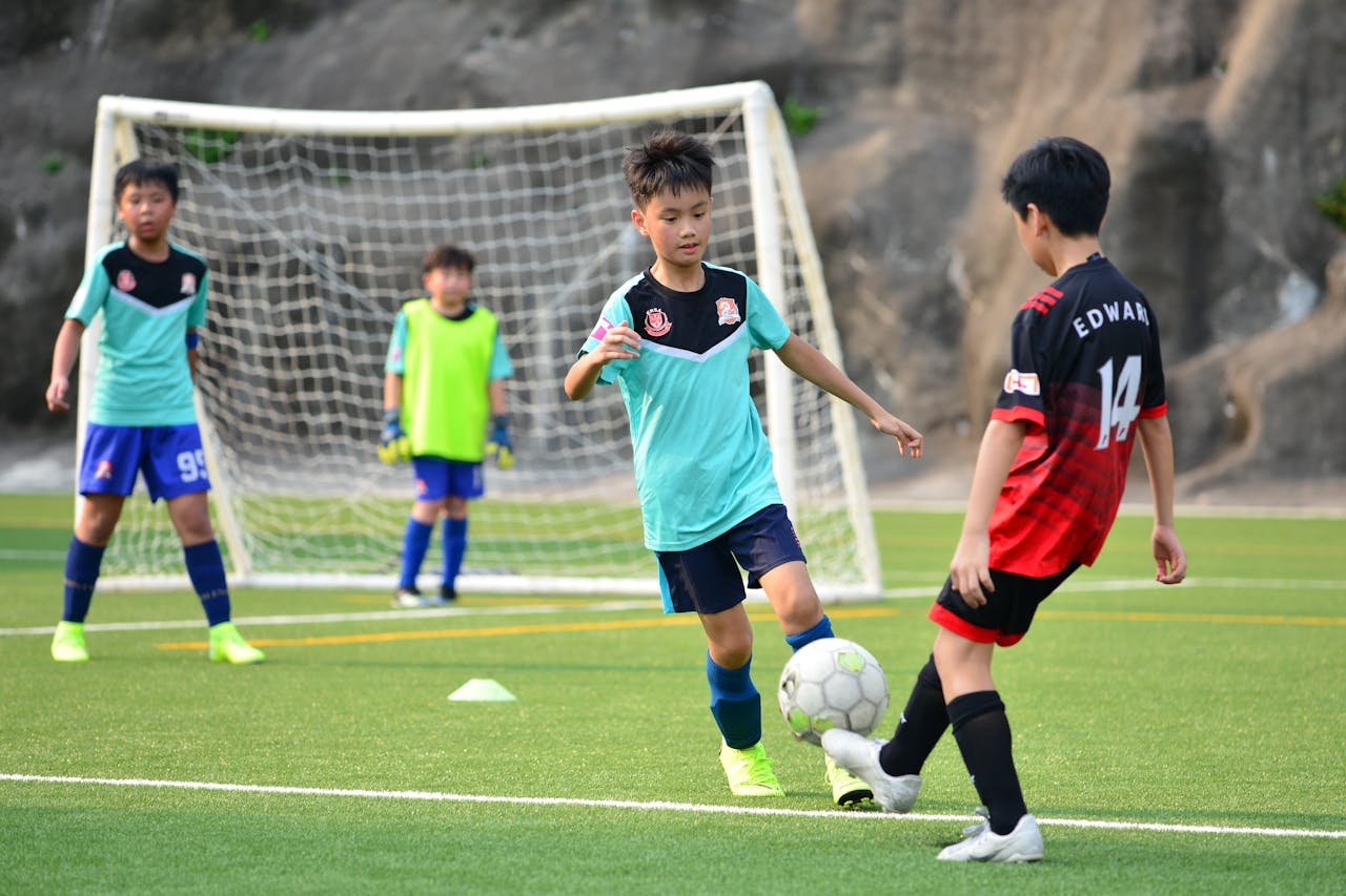 why-choose-us-02 Boys playing soccer during a team training session outdoors on a sunny day.