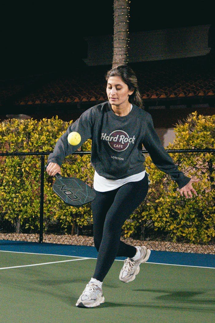 services-01 Energetic woman playing pickleball on an outdoor court under night lighting in Scottsdale, Arizona.